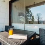 Terrasse mit Tisch, Stühlen und Glas. Im Hintergrund sind Bäume und ein Fenster sichtbar.
