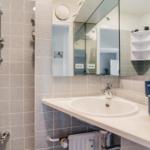 Badezimmer mit Dusche, Waschbecken und Spiegel