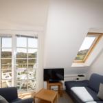 Living room with sofa, TV, and skylight. Door leads to balcony with view of landscape.
