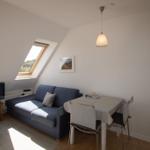 Living room with sofa, dining table, and skylight. TV and lighting are present.