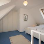 Bedroom with sloped ceiling, skylight, bed, and wardrobe.