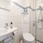 Badezimmer mit Dusche, Toilette und Waschbecken mit Spiegel.
