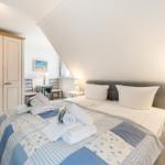 Schlafzimmer mit Doppelbett, Kleiderschrank und Nachttischen. Dachgeschoss mit schrägem Dach.