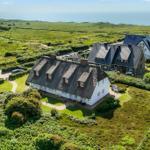 Haus mit strohgedecktem Dach, umgeben von Grünland und Meer.