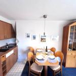 Kitchen with dining area, wooden table, chairs, hutch, and wall pictures.