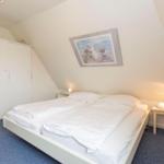 Bedroom with double bed, wardrobe, and nightstand under sloped walls.