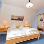 Bedroom with double bed, two nightstands, and mirror on the wall.