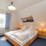 Bedroom with double bed, two nightstands, and window with blue curtains.