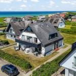 Moderne Villa mit Terrasse und Blick auf das Meer. Umgeben von Grünflächen und anderen Häusern.