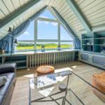 Dachgeschosswohnung mit großem Fenster, Sofa, Couchtisch und integriertem Schrank.
