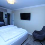 Bedroom with double bed, TV, and armchair.