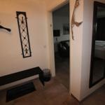 Entryway with wall coat rack, bench, and mirror. View into living and sleeping areas.
