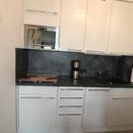 Kitchen with white cabinets, black countertop, and built-in oven.