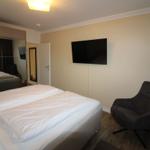 Bedroom with double bed, wall-mounted TV, and armchair.