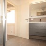 Badezimmer mit Glasdusche, Waschtisch und Spiegel