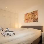 Schlafzimmer mit Doppelbett, Kleiderschrank und Wandbild mit Rosen.