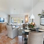 Living and dining area with TV, dining table, and windows to the outdoor terrace.