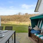 Terrace with table, chairs, and beach cabana with green-white stripes.