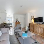 Living room with sofa, TV, and dining area. Wooden furniture and terracotta floor.