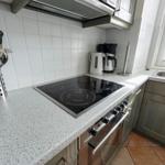 Kitchen with stove, sink, and kitchen utensils on the countertop.