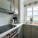 Kitchen with induction cooktop, sink, and window with blinds.