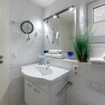 Bathroom with sink, mirror, and plant. Towels and shower fixture are available.