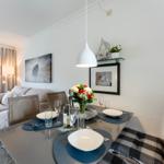 Dining table with chairs and set table. Background: sofa and wall art.