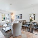 Living and dining area with sofa, table and chairs. Windows to the outside.