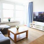 Wohnzimmer mit Sofa, Couchtisch und Fernseher an der Wand.