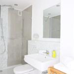 Badezimmer mit Dusche, Waschbecken und Spiegel.