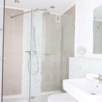 Badezimmer mit Dusche, Waschbecken und Spiegel