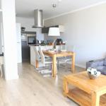 Wohn- und Essbereich mit Kücheninsel, Holztisch und grauem Sofa.