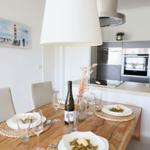 Essbereich mit Tisch, Stühlen und Küchenzeile im Hintergrund.