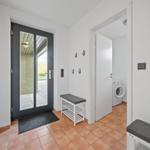 Eingangsbereich mit Glastür, Schuhschrank und Waschmaschine im Hintergrund.