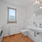 Badezimmer mit Waschmaschine, Toilette und Fenster