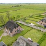 Dorfhaus mit Strohdach und Garten in grüner Landschaft