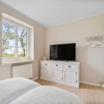 Schlafzimmer mit Fenster, TV-Schrank und Bett.