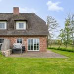 Haus mit Strohdach, Backsteinfassade und Terrasse mit Garten.