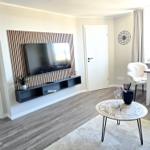 Living room with TV on wood wall, coffee table with compass design, and seating area.