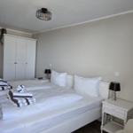 Bedroom with double bed, white nightstands, and wardrobe.