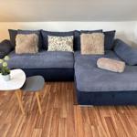 Ein graues Sofa mit Kissen und einem Beistelltisch auf Holzboden.