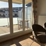 Durchgehendes Fenster mit Blick auf Balkon und Tisch. Holzboden und Stühle im Raum.