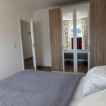 Schlafzimmer mit Bett, Spiegelschrank und Tür zum Flur.