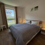 Schlafzimmer mit Doppelbett, Fenster und Nachttischen.