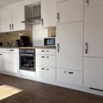 Moderne Küche mit weißen Schränken, Edelstahlgeräten und Holz Arbeitsplatte.