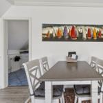 Esszimmer mit Tisch, Stühlen und Wandbild mit Segelbooten.