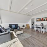 Wohn- und Essbereich mit Sofa, Tisch und Fenster. Decke mit Holzverkleidung.
