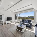 Wohnzimmer mit Sofa, Fernseher und Blick auf die Landschaft.