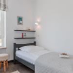 A bedroom with a bed, window, and shelves on the wall.