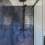 Shower with dark blue tiles and showerhead
